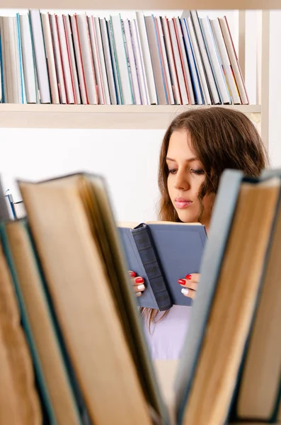 Jovem estudante se preparando para exames na biblioteca — Fotografia de Stock