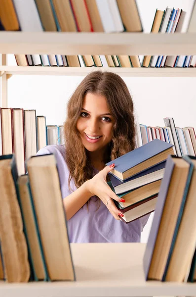 Ung kvinnlig student förbereder sig för tentamen på biblioteket — Stockfoto