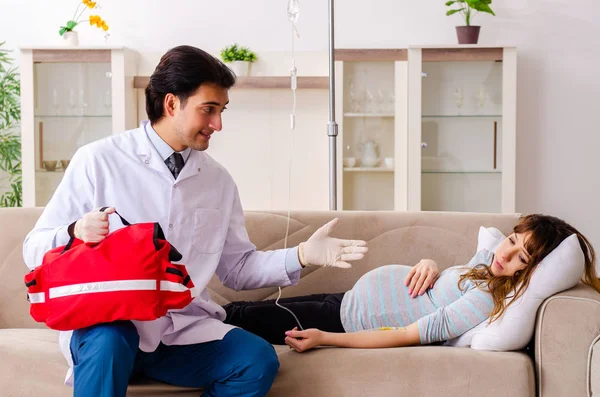 Jeune beau médecin visitant femme enceinte à la maison — Photo