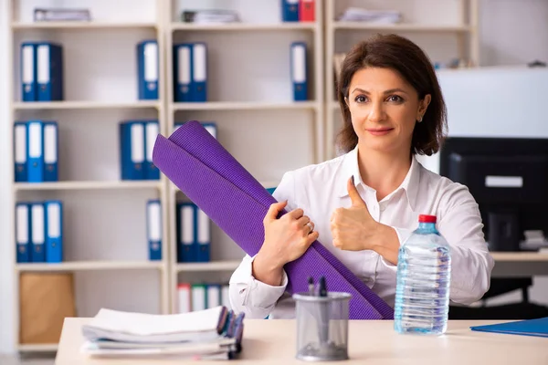 Middle-aged female employee doing exercises in the office — Stock Photo, Image