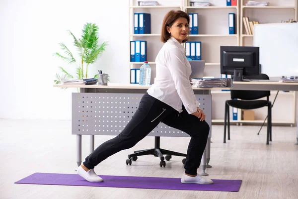 Impiegata di mezza età che fa esercizi in ufficio — Foto Stock