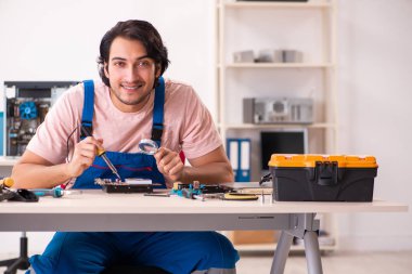 Genç bir erkek müteahhit bilgisayar tamir ediyor.