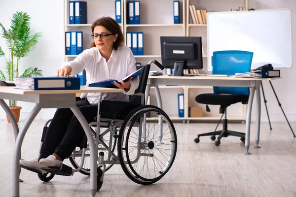 Сотрудница в инвалидной коляске в офисе — стоковое фото