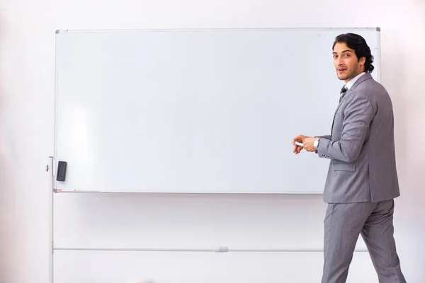 Ung snygg affärsman står framför whiteboard — Stockfoto