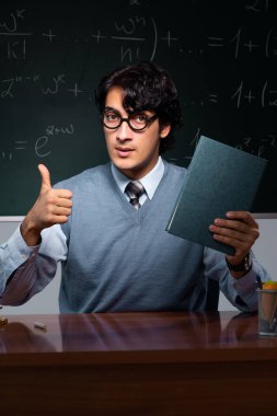 Young math teacher in front of chalkboard clipart