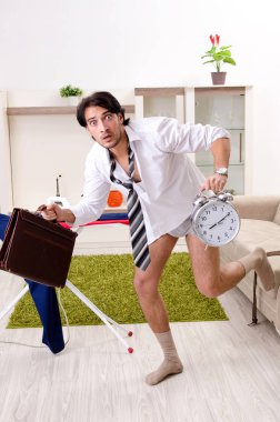 Genç adam yatak odasında ütü yapıyor.