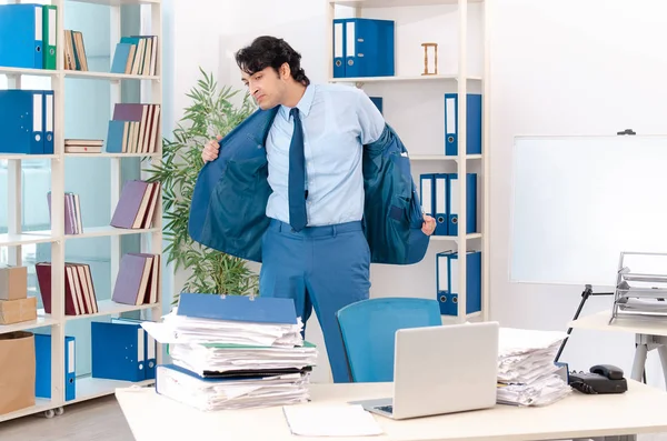 Joven empleado varón guapo con demasiado trabajo en la oficina — Foto de Stock