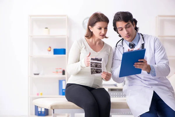 Vecchia donna incinta in visita giovane medico maschio — Foto Stock