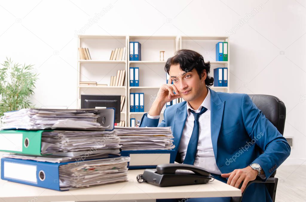 Young handsome busy employee sitting in office
