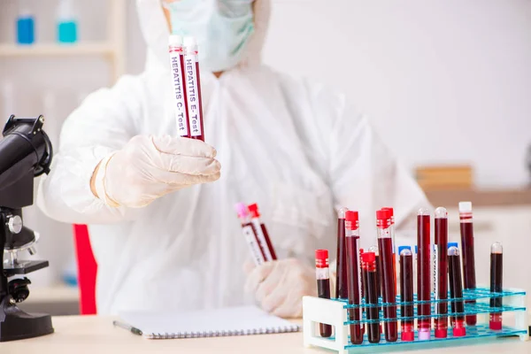 Asistente de laboratorio joven guapo analizando muestras de sangre en el hospital — Foto de Stock