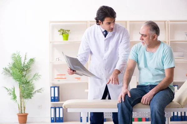 Homem velho visitando jovem médico masculino — Fotografia de Stock