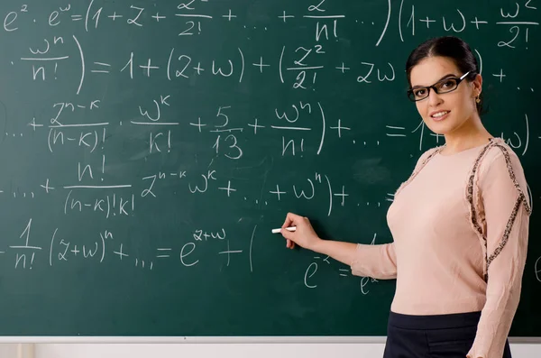 Female teacher standing in front of chalkboard — Stock Photo, Image