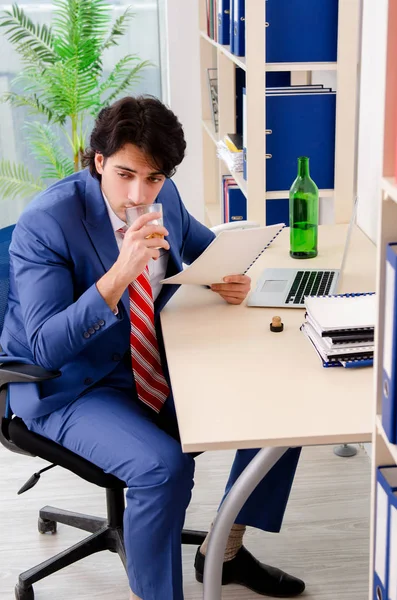 Молодой бизнесмен пьет в офисе — стоковое фото