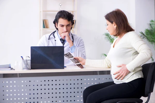 Oude zwangere vrouw bezoekende jonge mannelijke arts — Stockfoto