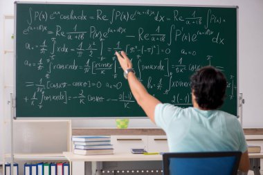 Kara tahta önünde genç erkek öğrenci matematikçi