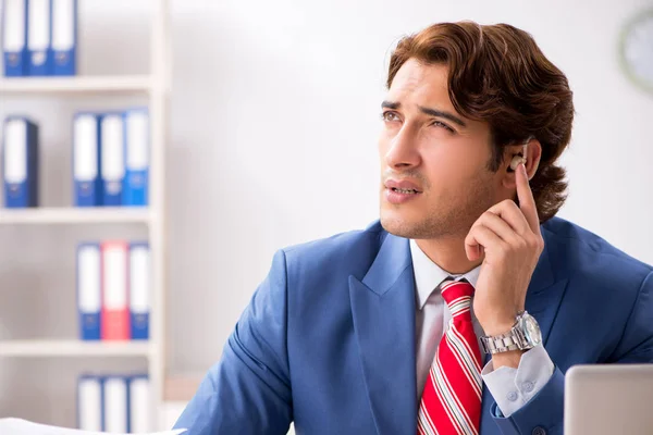 Empleado sordo usando audífono en la oficina — Foto de Stock