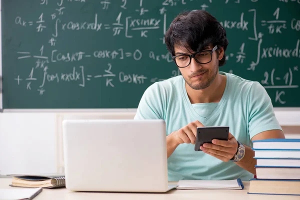 Joven matemático estudiante masculino frente a pizarra — Foto de Stock