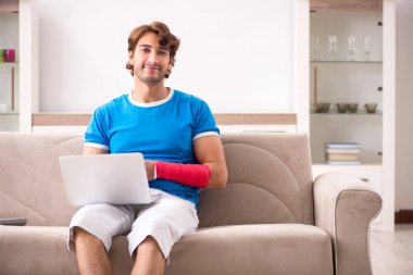 Yaralı kollu kanepede oturan genç adam