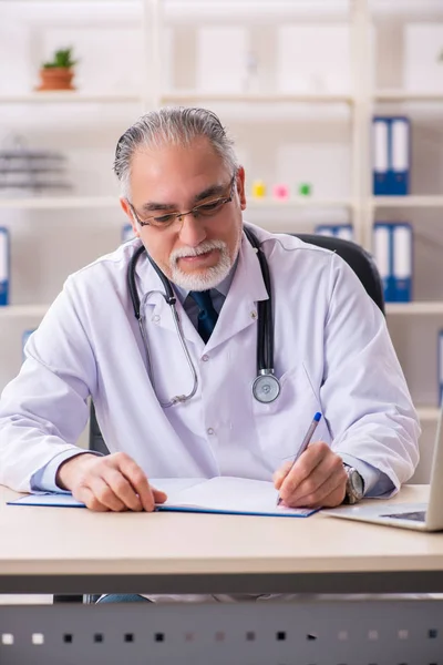 Klinikte çalışan yaşlı erkek doktor. — Stok fotoğraf