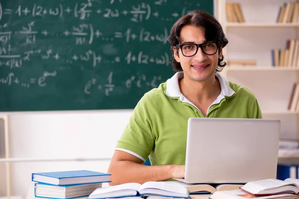 Handsome student in front of chalkboard with formulas — Stock Photo, Image