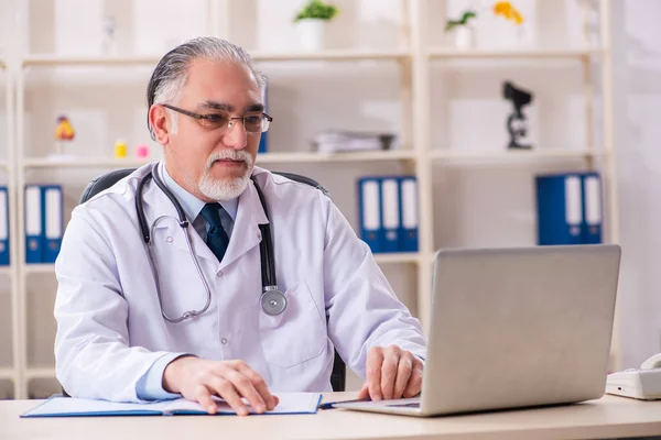 Åldrad manlig läkare som arbetar på kliniken — Stockfoto