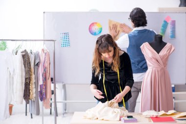 Genç erkek terzi kız öğrenciye öğretmenlik yapıyor. 