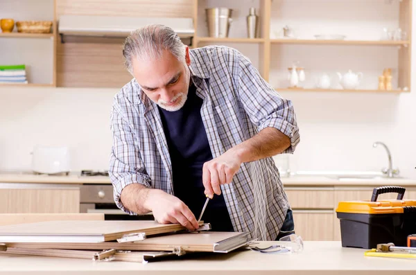 Reparador de empreiteiro envelhecido que trabalha na cozinha — Fotografia de Stock