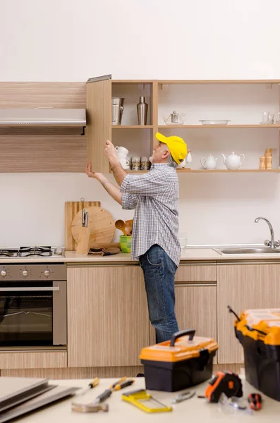 Reparador de empreiteiro envelhecido que trabalha na cozinha — Fotografia de Stock