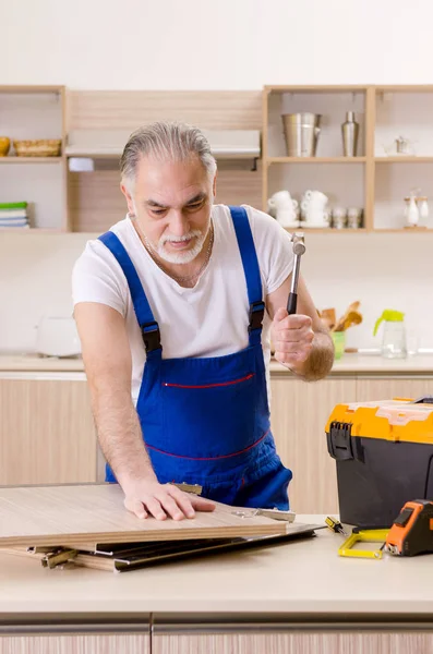 Reparador de empreiteiro envelhecido que trabalha na cozinha — Fotografia de Stock