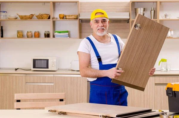 Reparador de empreiteiro envelhecido que trabalha na cozinha — Fotografia de Stock