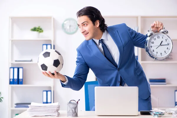 Jovem empresário bonito com bola de futebol no escritório — Fotografia de Stock