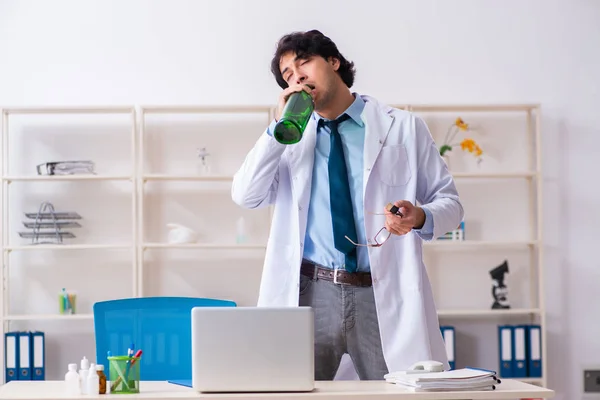 Joven doctor bebiendo en el consultorio — Foto de Stock