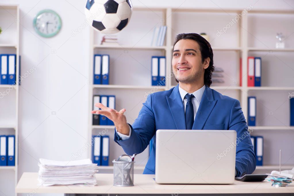 Young handsome businessman with soccer ball in the office 