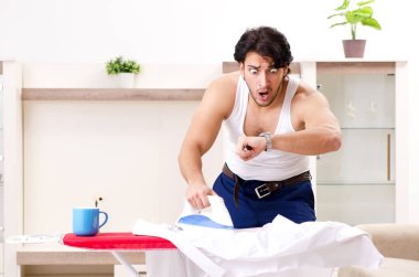 Genç adam yatak odasında ütü yapıyor.