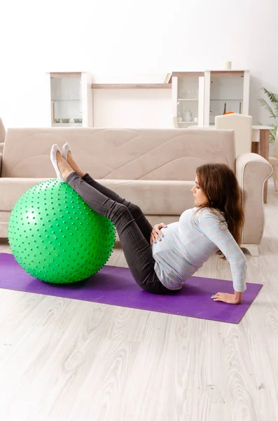 Mujer embarazada joven haciendo ejercicios deportivos en casa — Foto de Stock