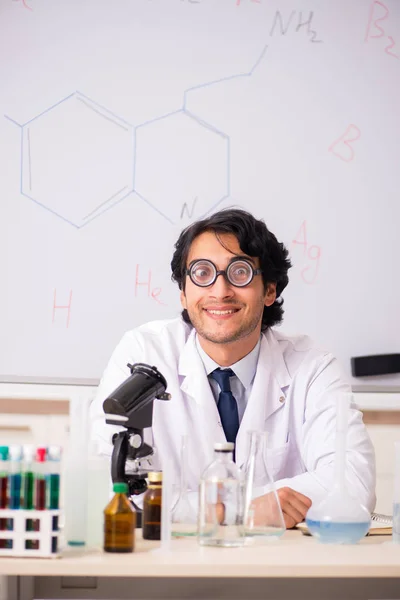 Joven químico divertido delante de la pizarra blanca — Foto de Stock