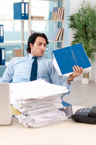 Mladý pohledný muž zaměstnanec s příliš mnoho práce v kanceláři — Stock fotografie