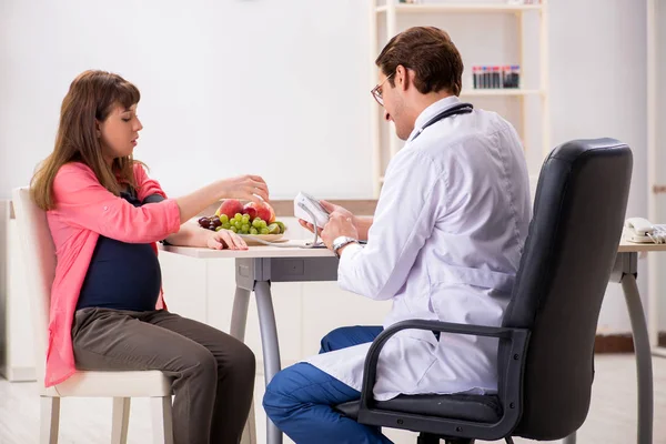 Pregnant woman visiting doctor discussing healthy diet — Stock Photo, Image