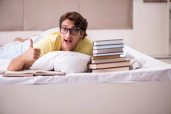 Jovem estudante estudando na cama para exames — Fotografia de Stock