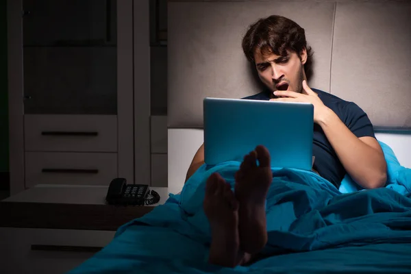 Homem trabalhando no laptop à noite na cama — Fotografia de Stock