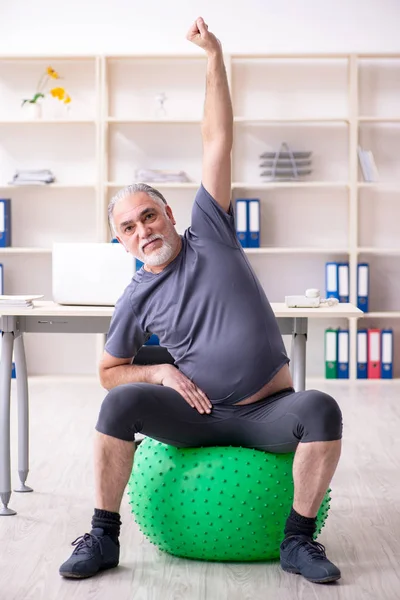 Mitarbeiter mit weißem Bart macht Übungen im Büro — Stockfoto