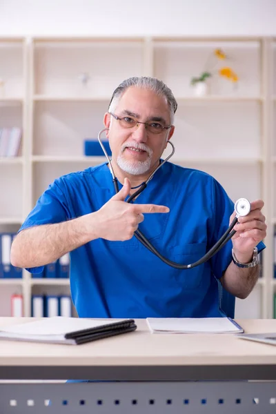 Белый бородатый старый врач, работающий в клинике — стоковое фото
