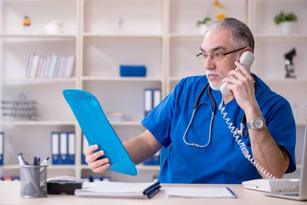 Beyaz sakallı yaşlı doktor klinikte çalışan — Stok fotoğraf