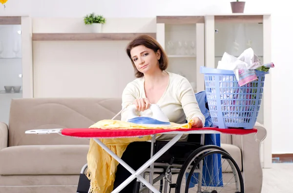 Mujer en silla de ruedas planchado en casa —  Fotos de Stock