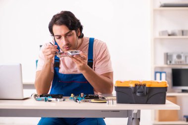 Genç bir erkek müteahhit bilgisayar tamir ediyor.  