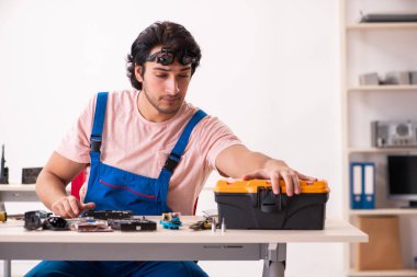 Genç bir erkek müteahhit bilgisayar tamir ediyor.  