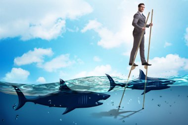 Köpekbalıkları arasında stilts üzerinde yürüyen işadamı