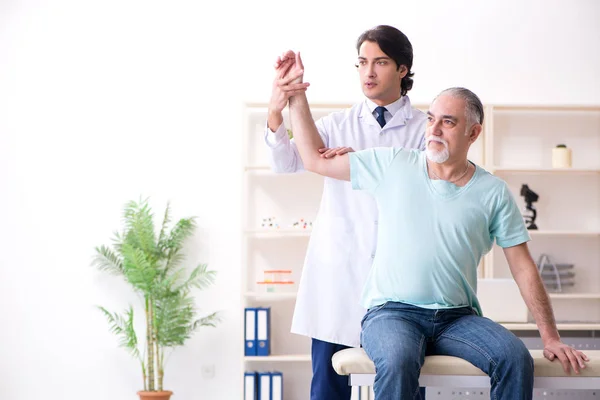 Viejo visitando joven doctor masculino — Foto de Stock