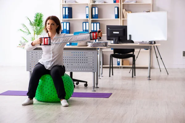 Жінка середнього віку робить вправи в офісі — стокове фото