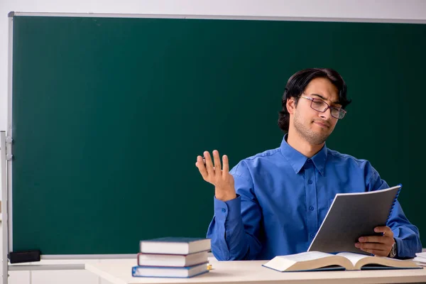 Young male teacher in front of chalkboard — Stock Photo, Image